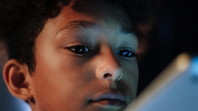 Le visage d'un enfant éclairé par la lumière bleue d'un écran, les yeux fixes, l'attention captée. La peau réfléchit la température de couleur de l'écran. Ce n'est pas une image dramatique, c'est une image ordinaire. C'est ce qui se passe dans presque toutes les maisons, chaque soir.