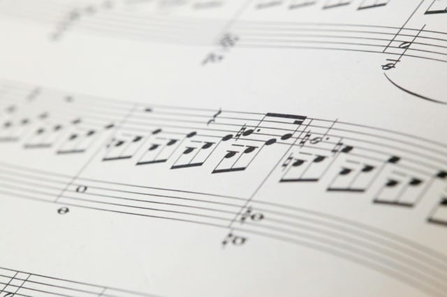 Una pagina di partitura musicale ravvicinata, le note nere allineate sulle pentagrammi, il pentagramma stesso come griglia rigorosa che rende possibile la composizione. Il vincolo come forma.